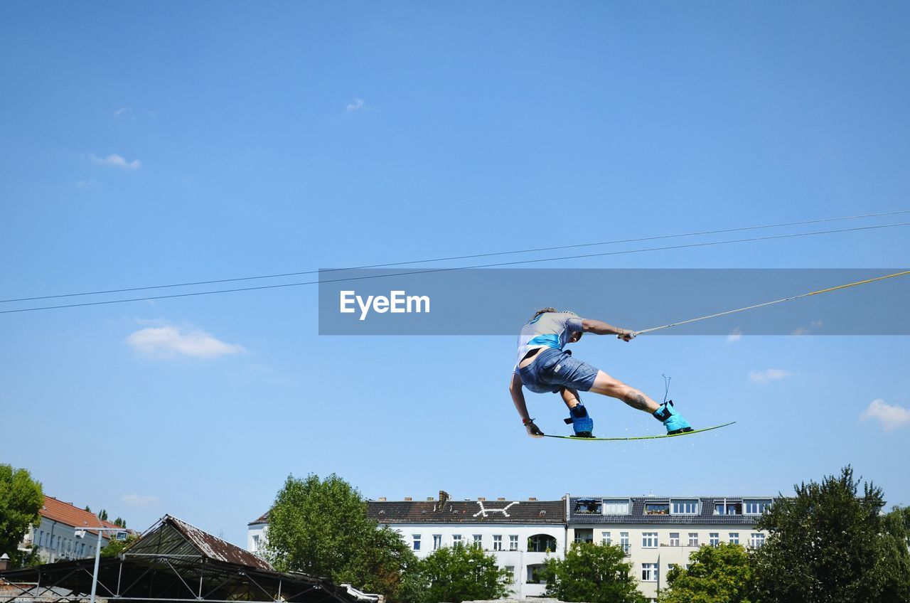 Low angle view of man in mid-air while kiteboarding