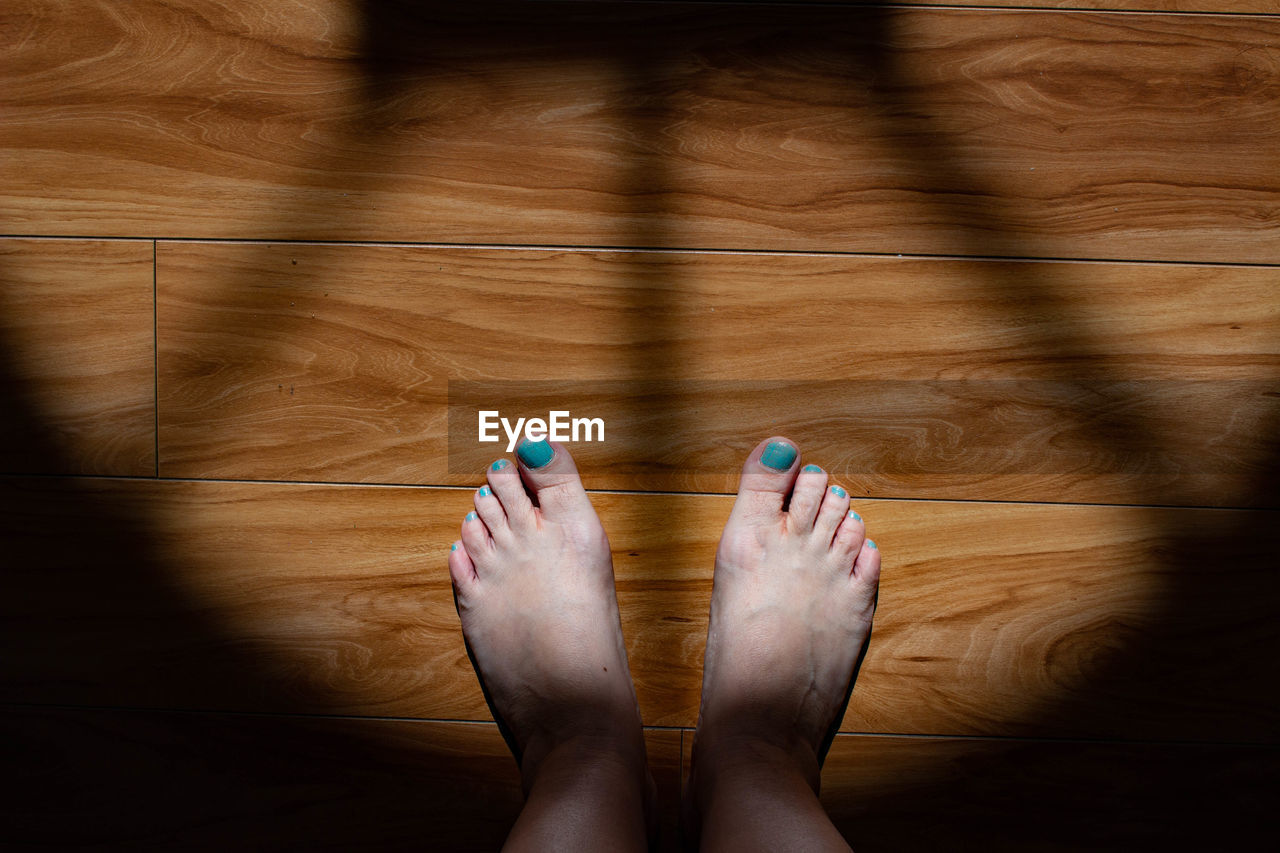 Low section of woman standing on wooden floor