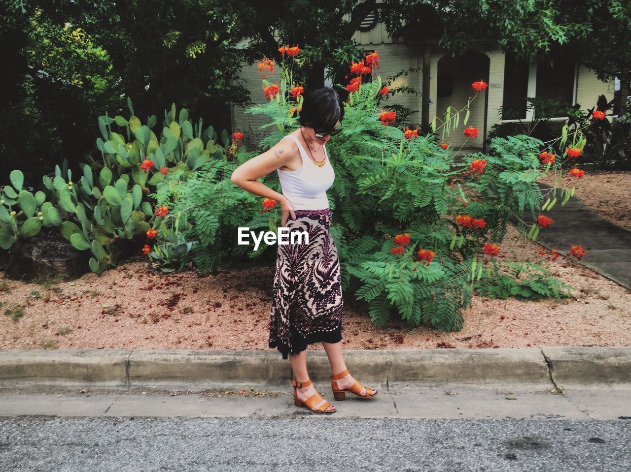 Full length of woman standing on footpath by plants