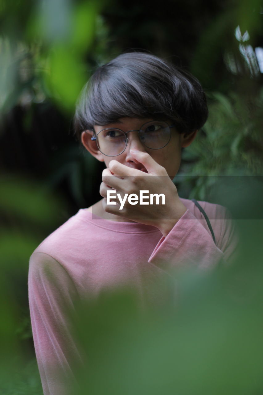 Young an looking away while standing by plants