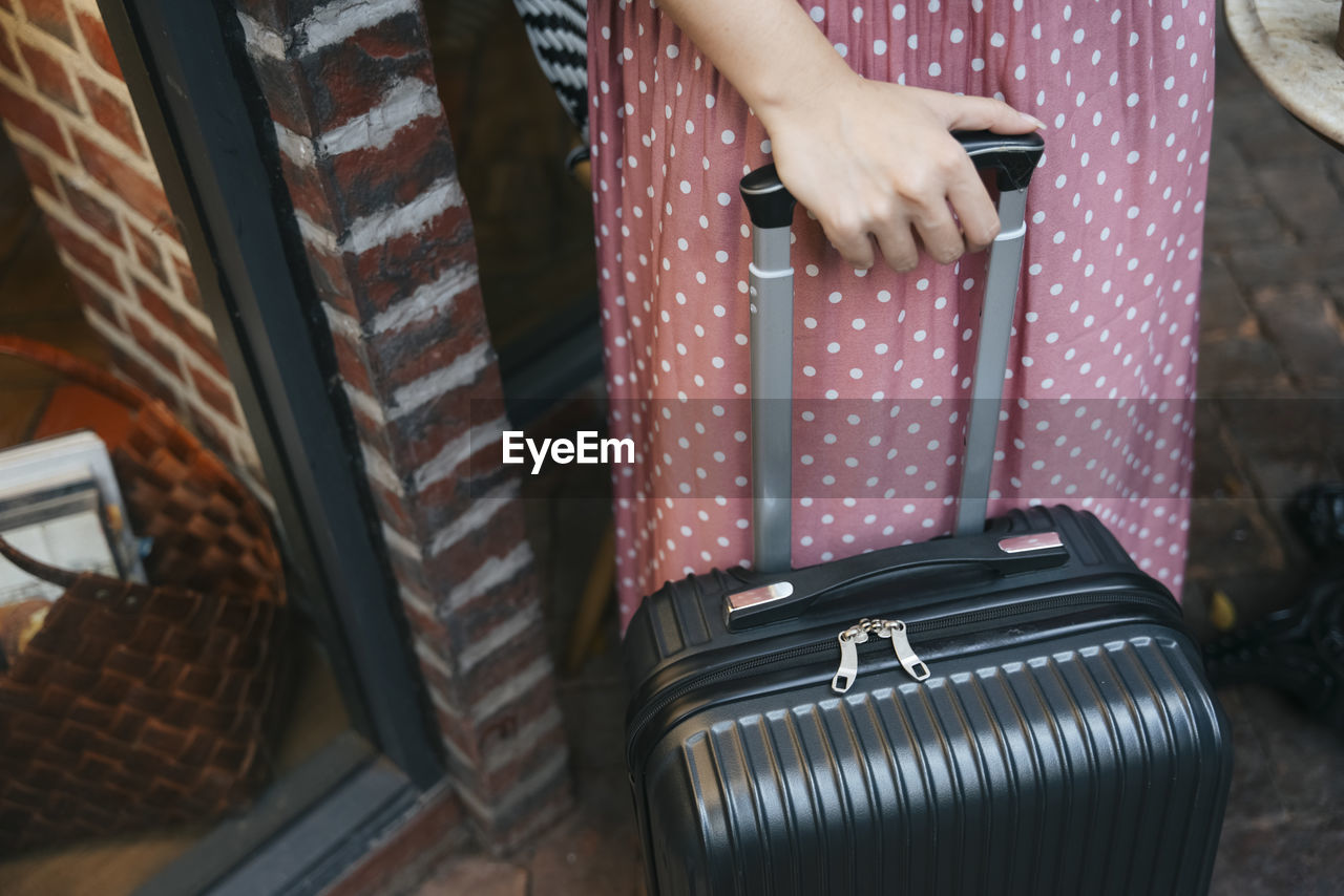 Midsection of woman holding suitcase