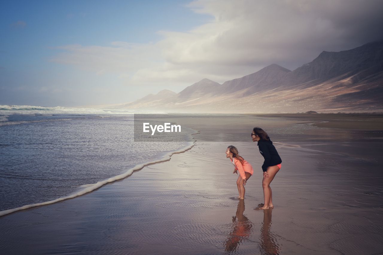 Friends enjoying at beach against sky