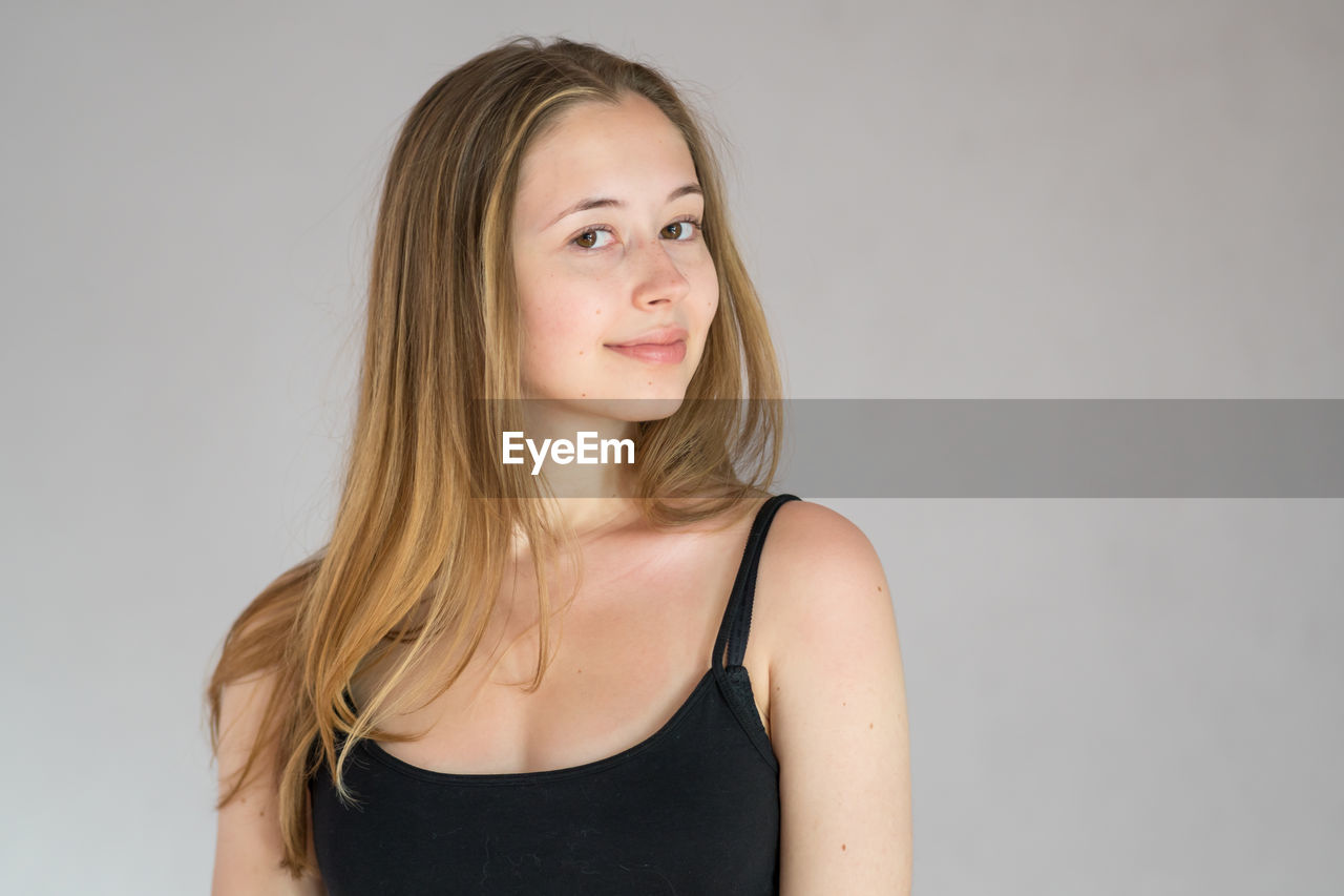 PORTRAIT OF YOUNG WOMAN AGAINST WHITE BACKGROUND