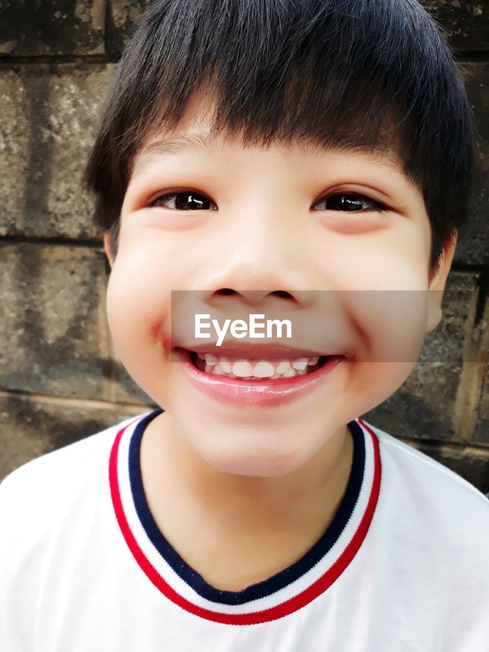 Close-up portrait of smiling boy against wall