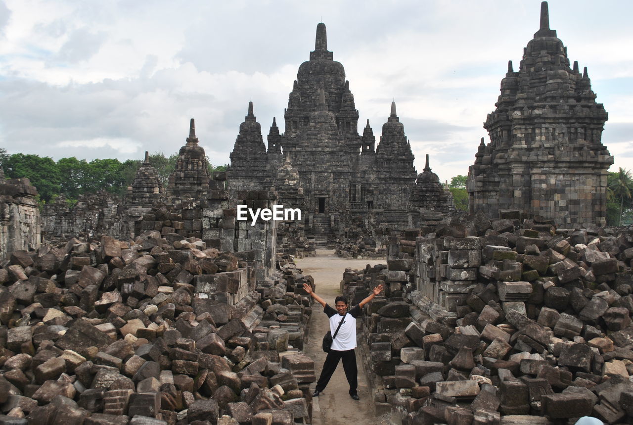 High angle view of man with arms raised standing amidst old ruins