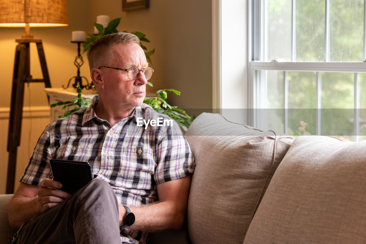 MIDSECTION OF MAN USING PHONE AT HOME