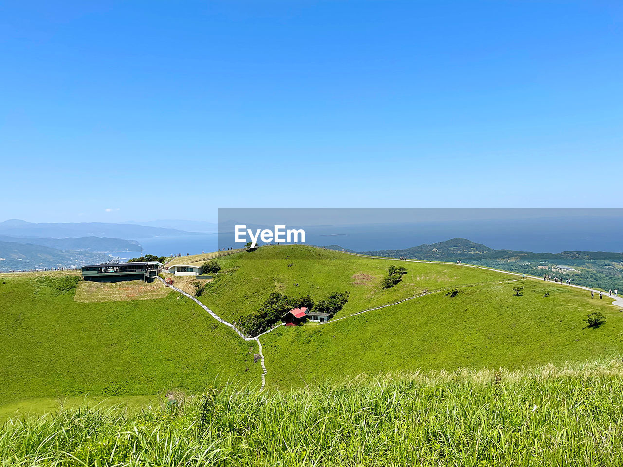 grassland, scenics - nature, landscape, land, sky, environment, plant, hill, nature, beauty in nature, grass, pasture, meadow, green, water, field, blue, tranquility, tranquil scene, rural scene, sea, plateau, plain, day, clear sky, travel, non-urban scene, mountain range, agriculture, architecture, idyllic, outdoors, no people, horizon, travel destinations, rural area, building, sunlight, tourism, growth, built structure, ridge, sunny, copy space, prairie, farm, summer, beach