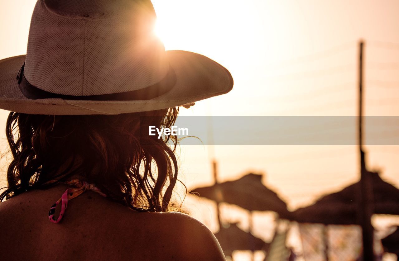 Rear view headshot of woman at beach against sky