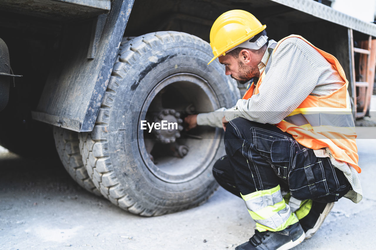 Mechanic inspecting truck tire outdoors