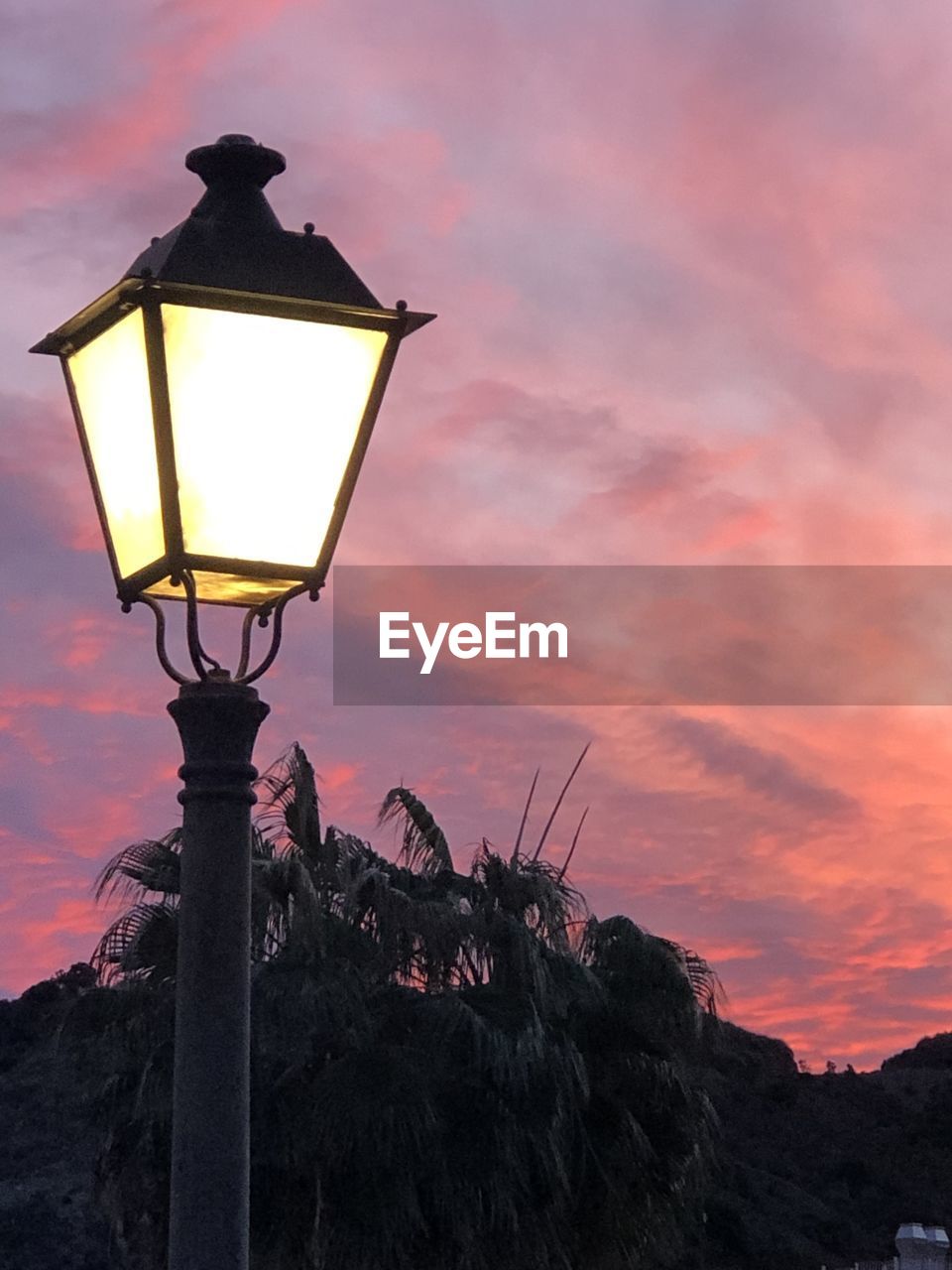 LOW ANGLE VIEW OF ILLUMINATED STREET LIGHT AGAINST ORANGE SKY