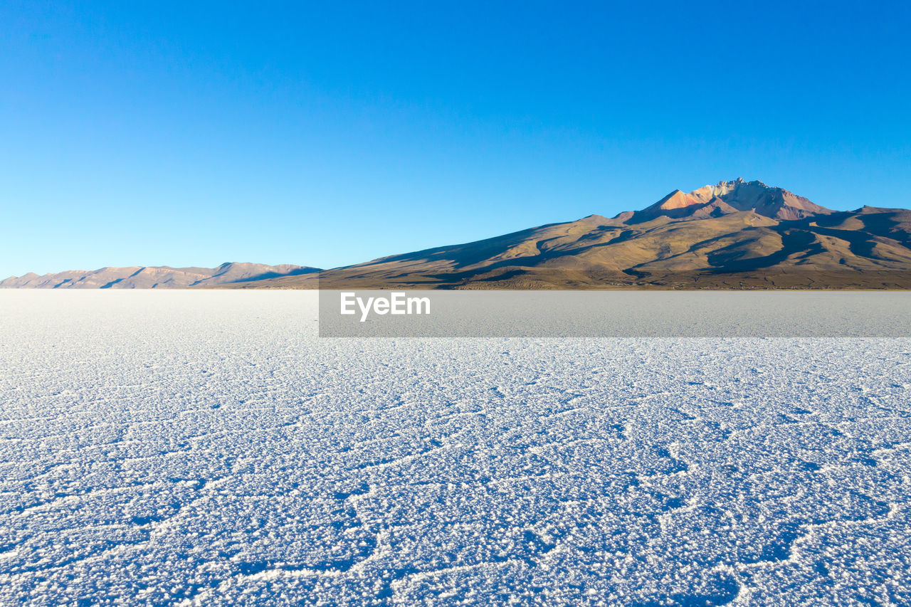 Scenic view of snowcapped mountains against clear blue sky