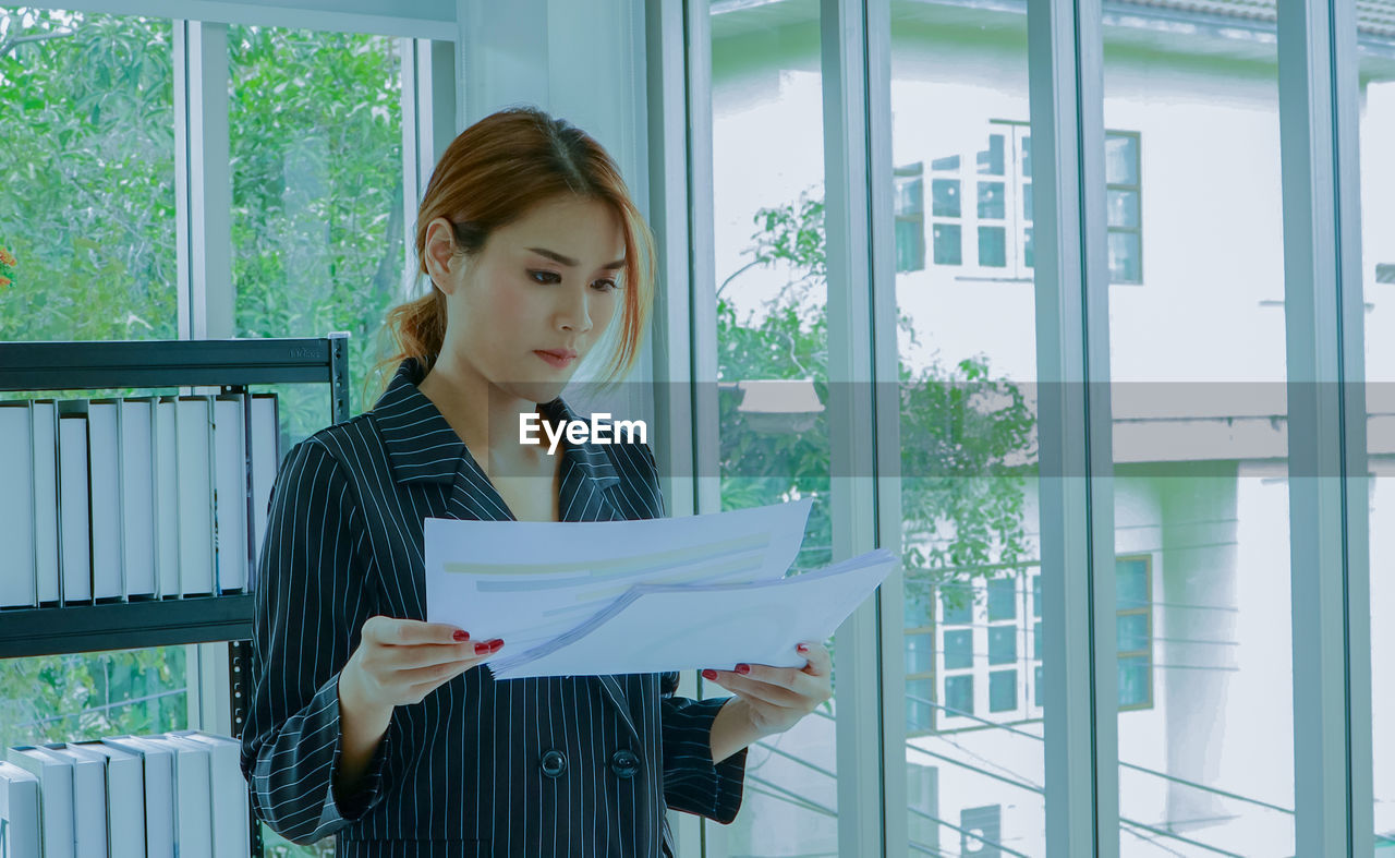 Young businesswoman holding papers at office