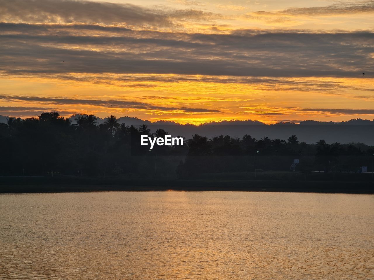 sky, sunset, scenics - nature, beauty in nature, tranquility, tree, water, tranquil scene, cloud, environment, landscape, nature, plant, no people, lake, orange color, land, horizon, idyllic, dawn, afterglow, sun, silhouette, reflection, non-urban scene, outdoors, forest, dramatic sky, sunlight, evening, travel destinations, mountain