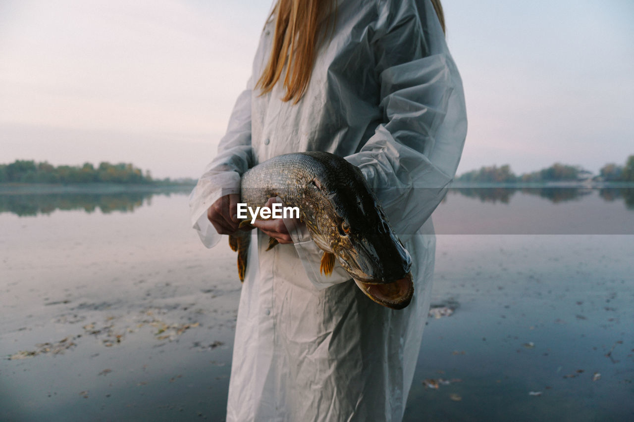 Midsection of young woman holding fish