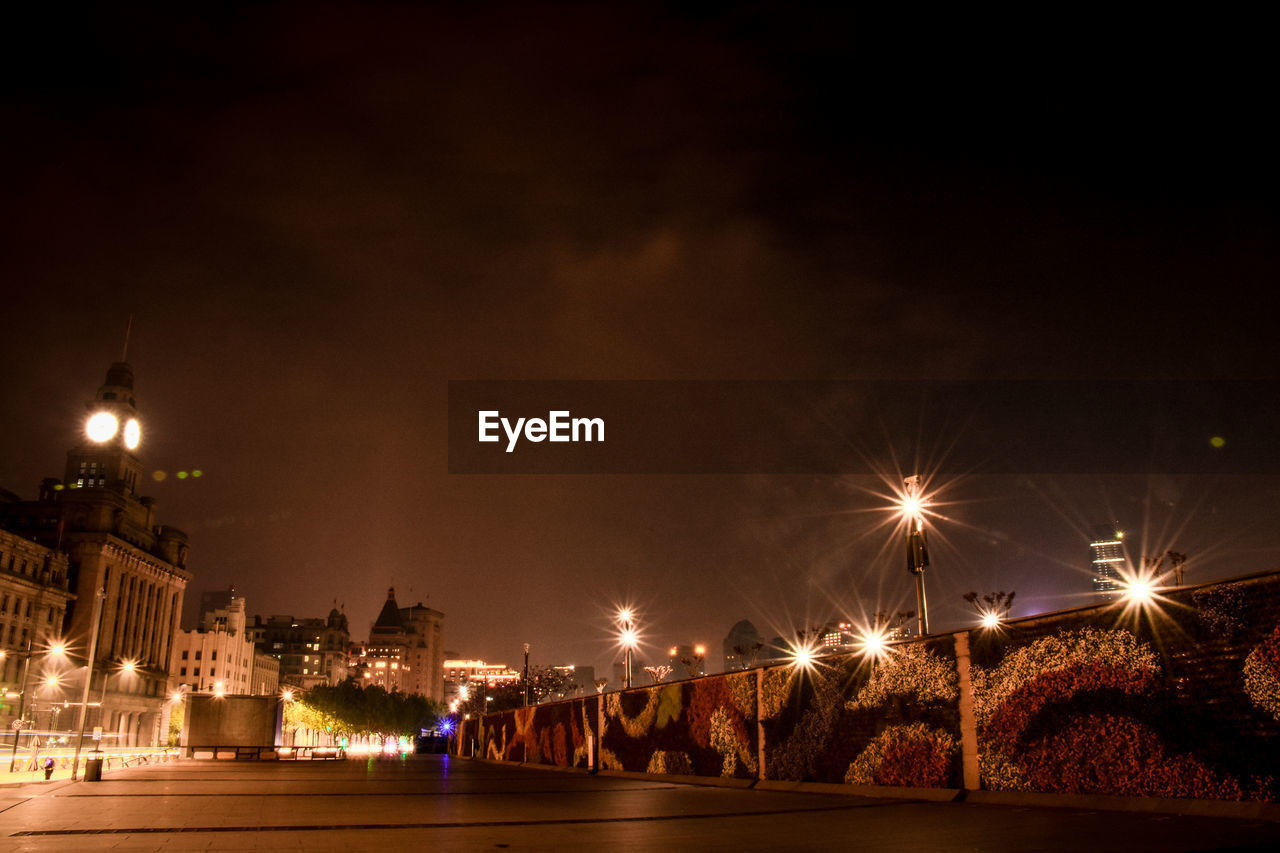 ILLUMINATED CITY BY RIVER AGAINST SKY