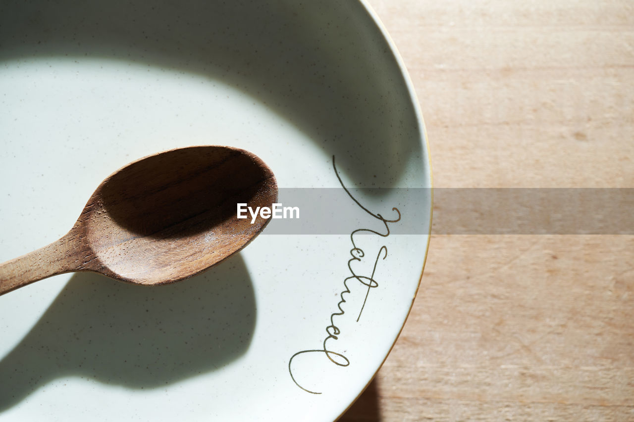 Wooden spoon on empty plate with text natural