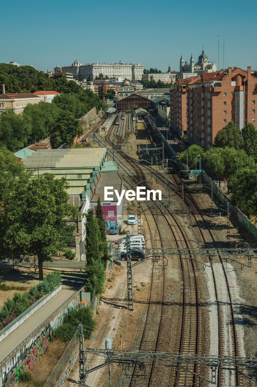 Royal palace and almudena cathedral on the horizon and a train station with rails in madrid, spain.