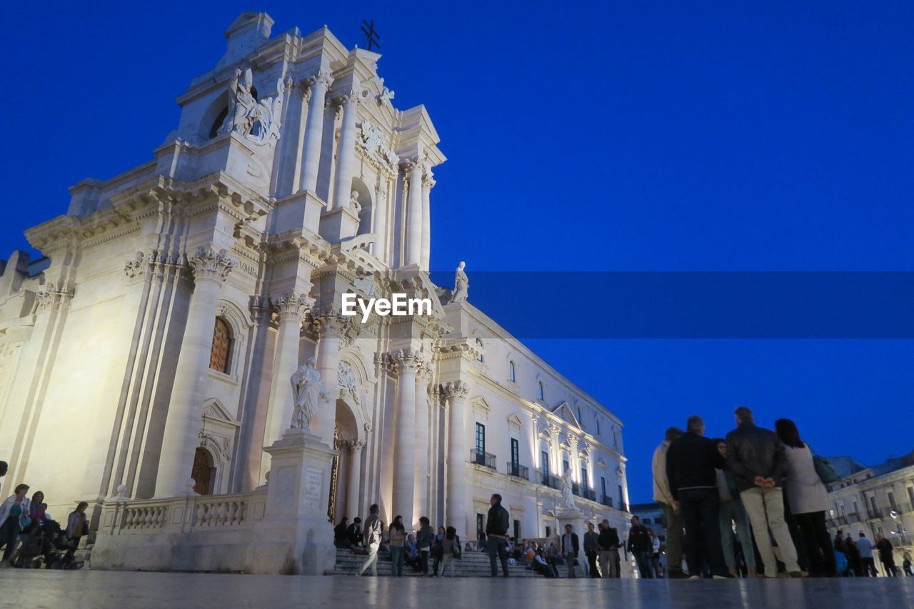 LOW ANGLE VIEW OF TOURISTS AGAINST CLEAR SKY