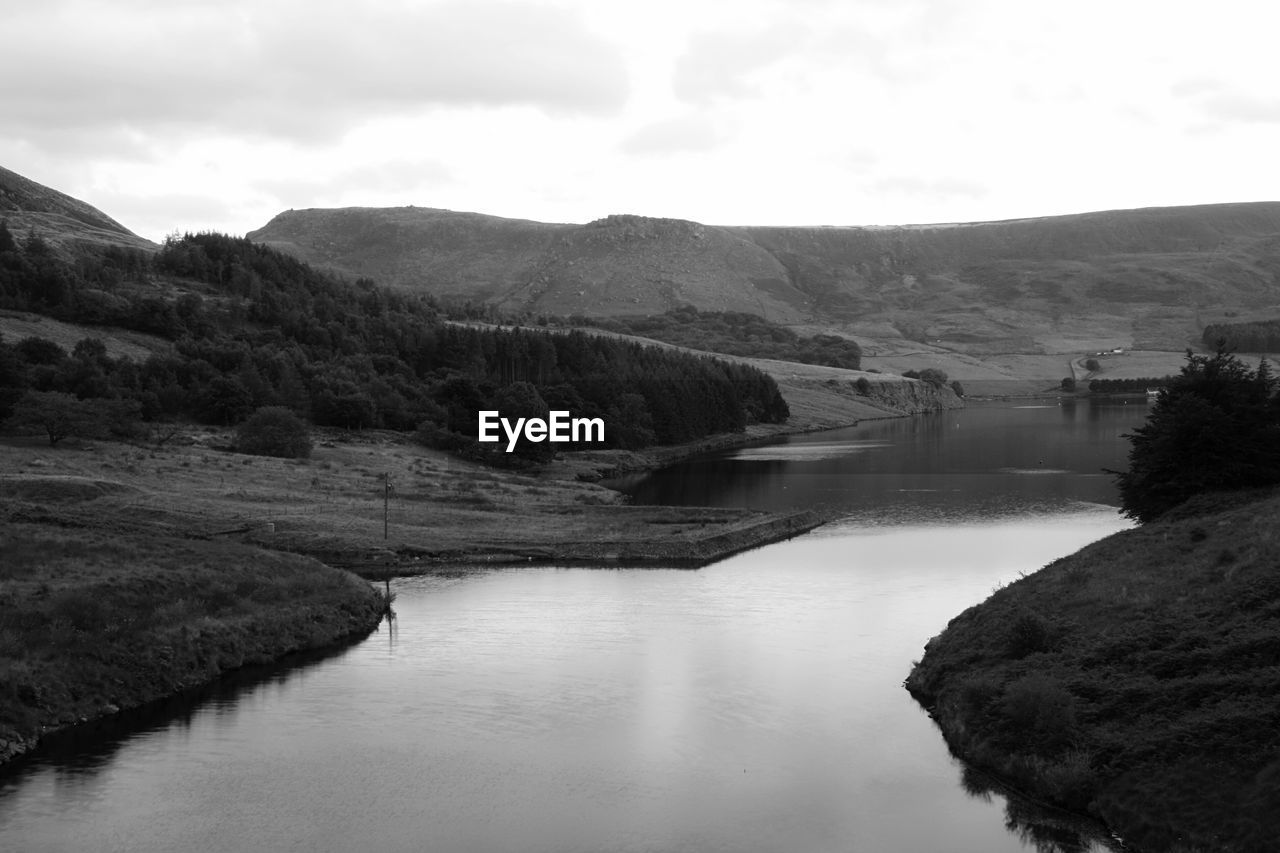 Scenic view of river by mountains against sky