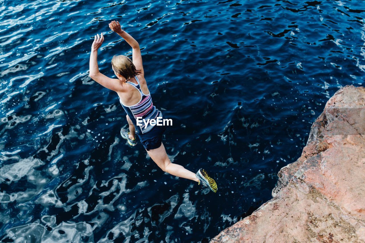 High angle view of woman jumping into the sea