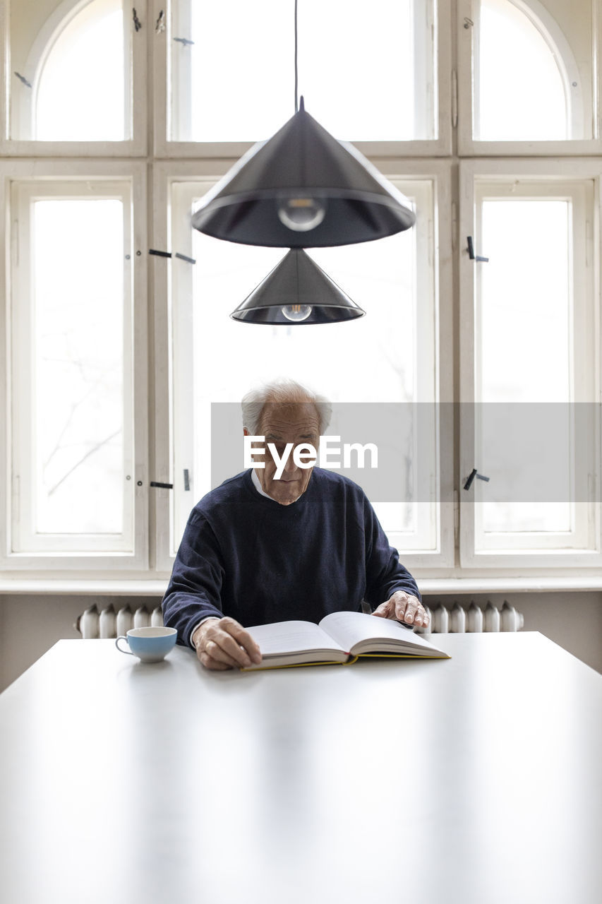 Senior man reading book at table at home