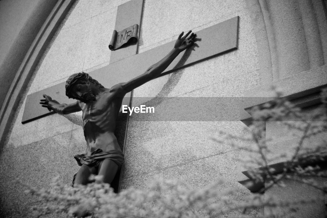 Low angle view of jesus christ statue with cross on wall