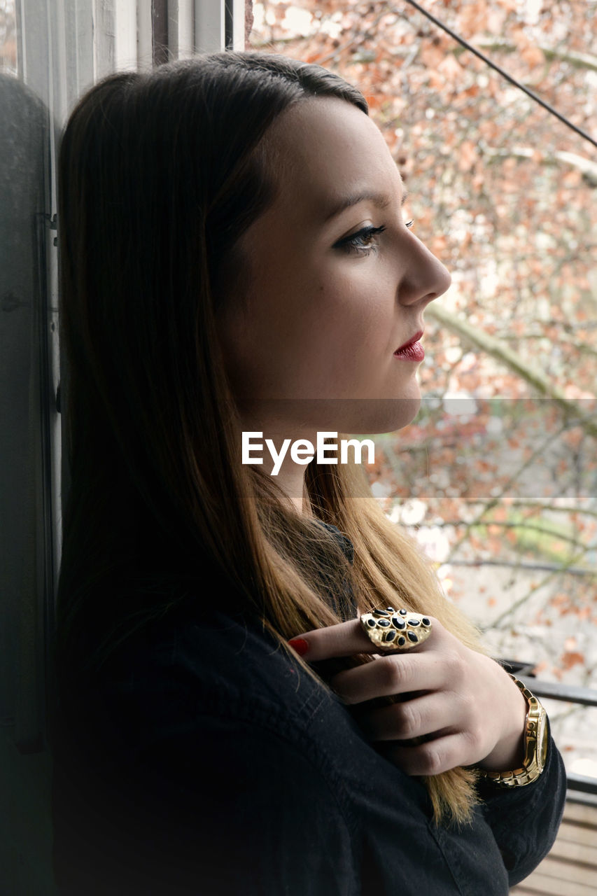 Side view of thoughtful beautiful woman leaning on wall