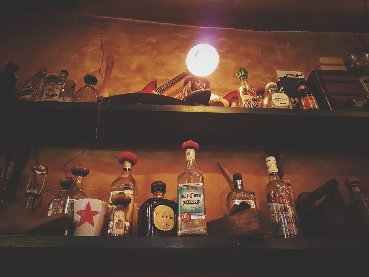 CLOSE-UP OF ILLUMINATED BOTTLES IN SHELF