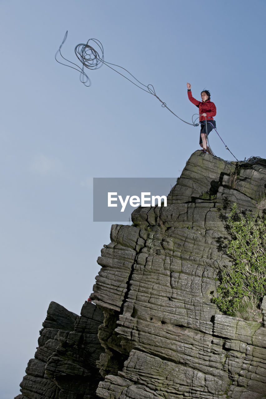 Woman throwing rope at windgather rocks in the british peak district