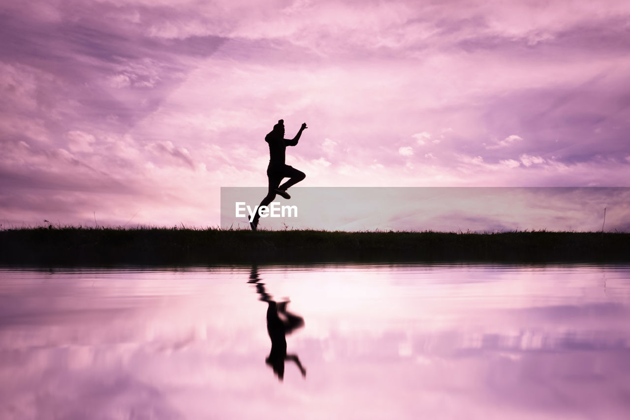 water, reflection, sky, lake, silhouette, cloud, one person, nature, sunset, adult, beauty in nature, tranquility, full length, vitality, sports, jumping, arm, pink, tranquil scene, lifestyles, men, scenics - nature, balance, motion, outdoors, activity, dusk, leisure activity, limb, exercising, arms raised, human limb