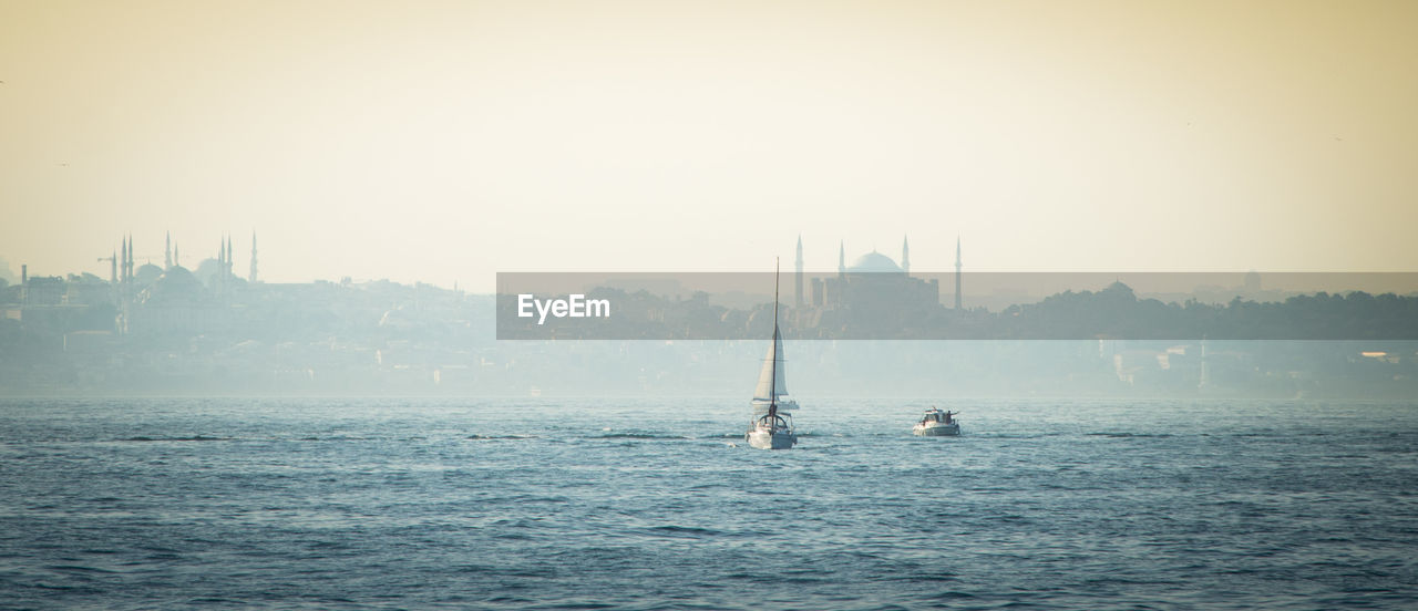 Sailboats sailing in sea against clear sky