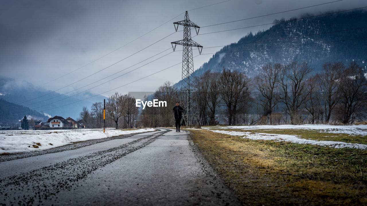 snow, electricity, winter, cold temperature, cable, electricity pylon, sky, transportation, road, nature, power line, technology, power supply, environment, tree, mountain, morning, plant, scenics - nature, landscape, cloud, freezing, beauty in nature, the way forward, power generation, architecture, mode of transportation, land, city, no people, outdoors, street, day, built structure, travel, frozen, storm, tranquility, tranquil scene, sunlight