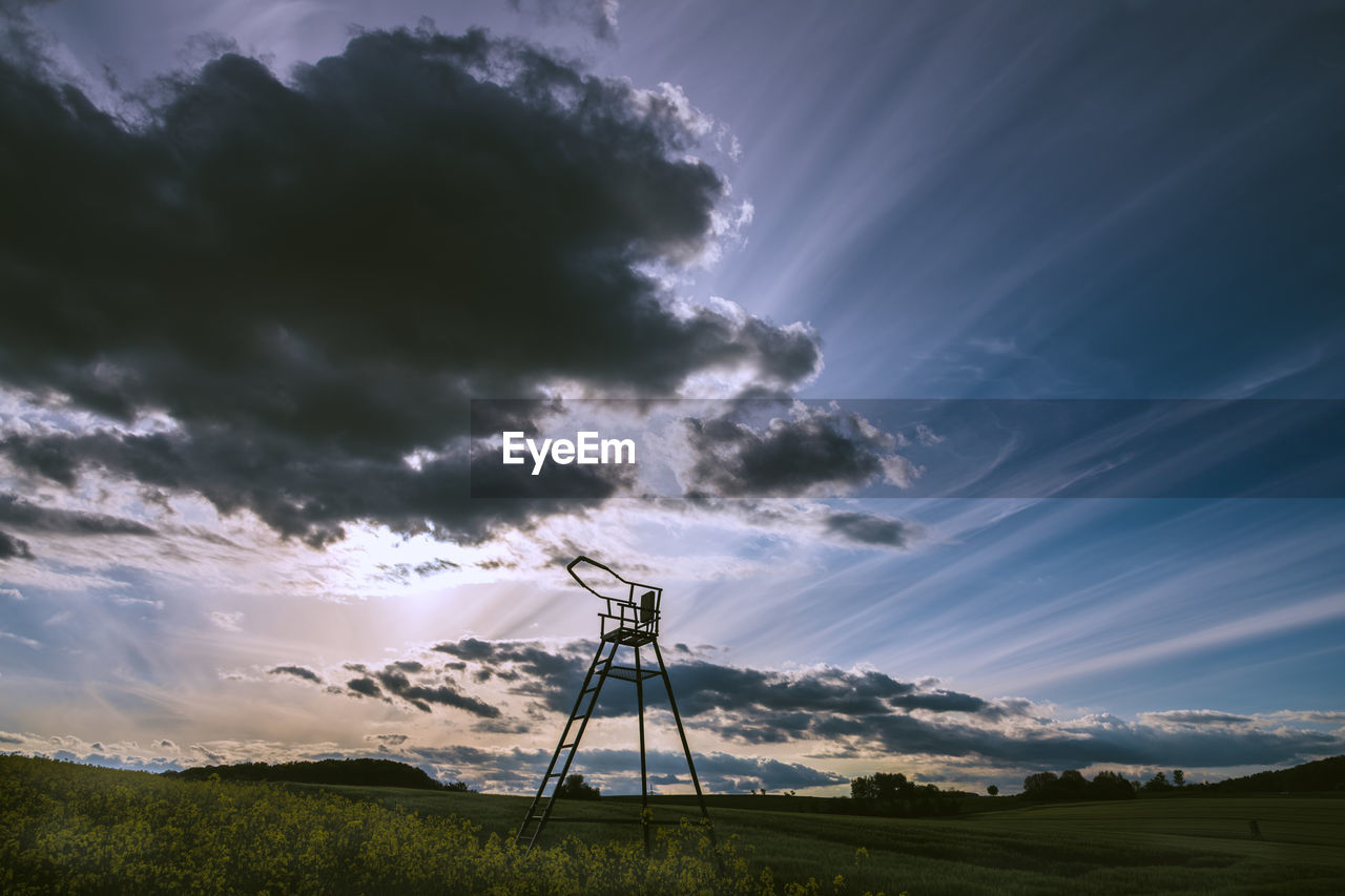 Low angle view of silhouette windmill on field against sky