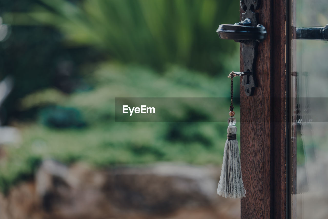 Key with a tassel key ring in the open door leading to the garden, selective focus.