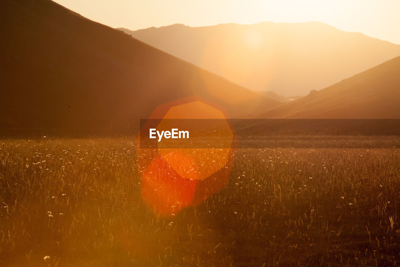 Idyllic shot of landscape against silhouette mountains during sunset