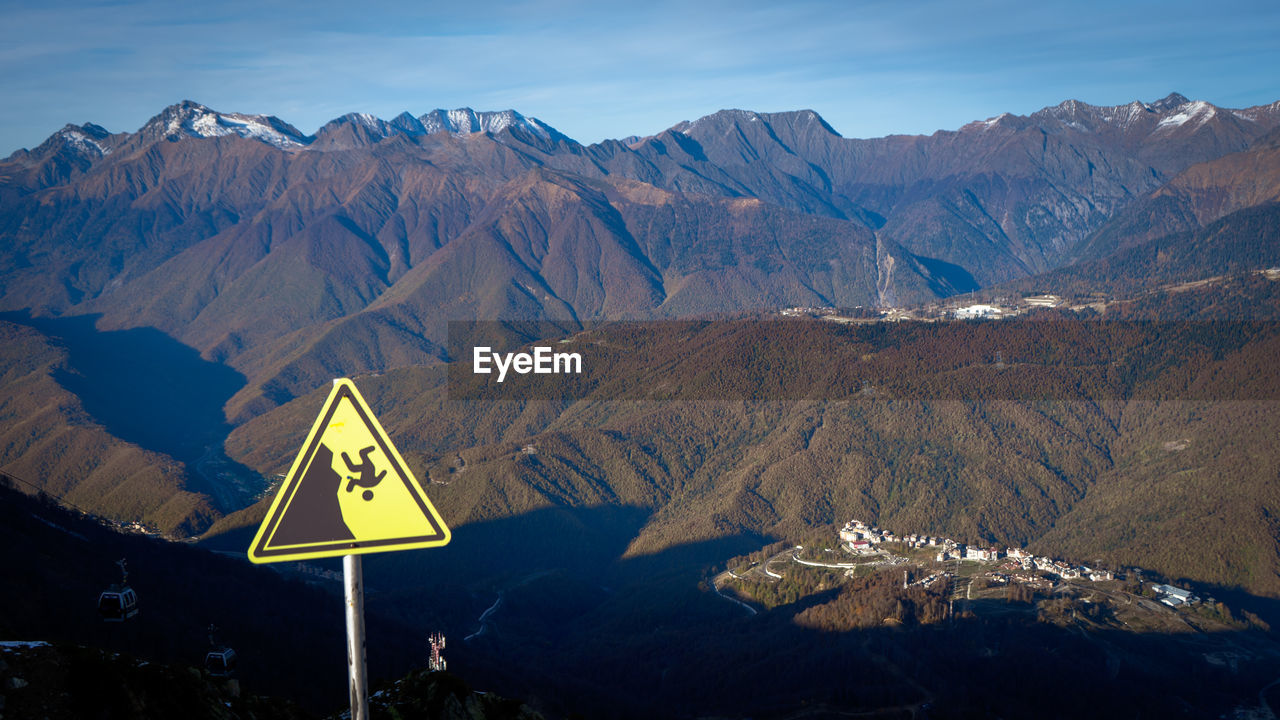 Road sign by mountains against sky