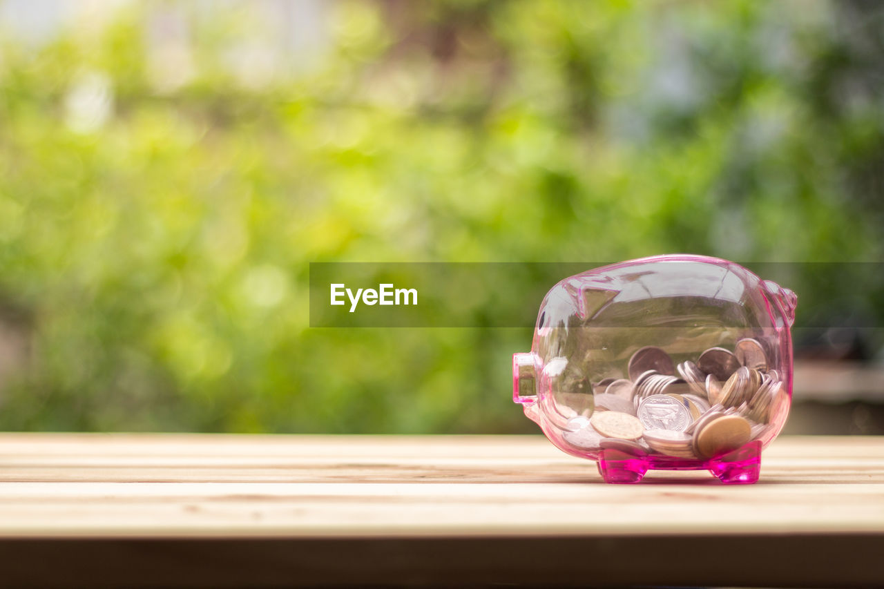 Coins in piggy bank on table