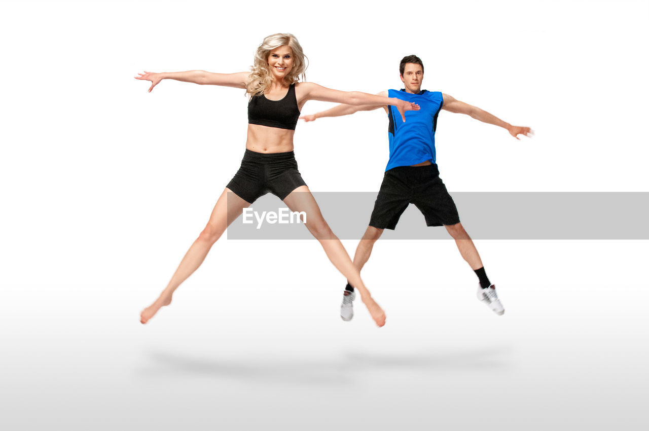 WOMAN JUMPING OVER WHITE BACKGROUND