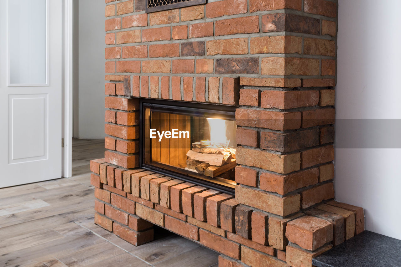 Firewood burning at fireplace surrounded by bricks