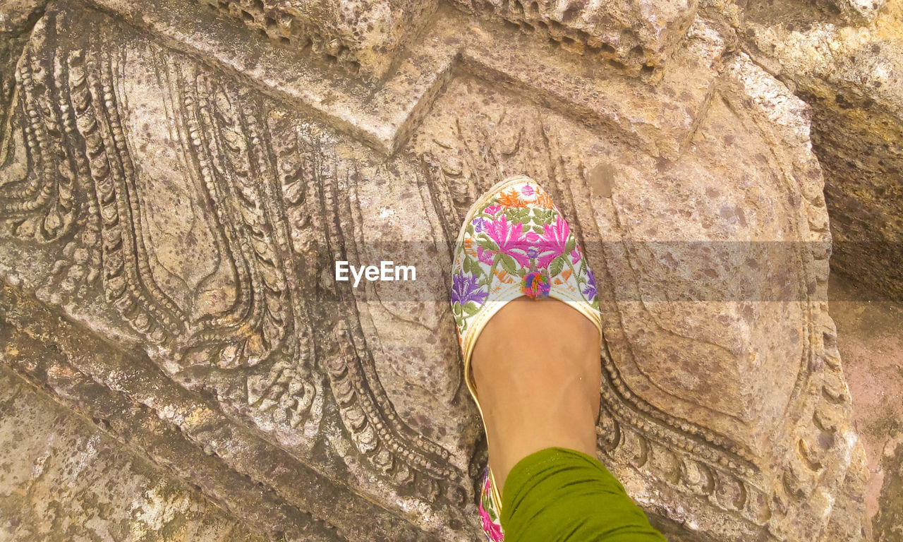 Low section of woman standing on beautiful ancient carved rock