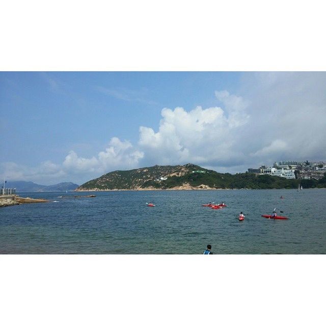 BOATS IN SEA WITH MOUNTAIN IN BACKGROUND