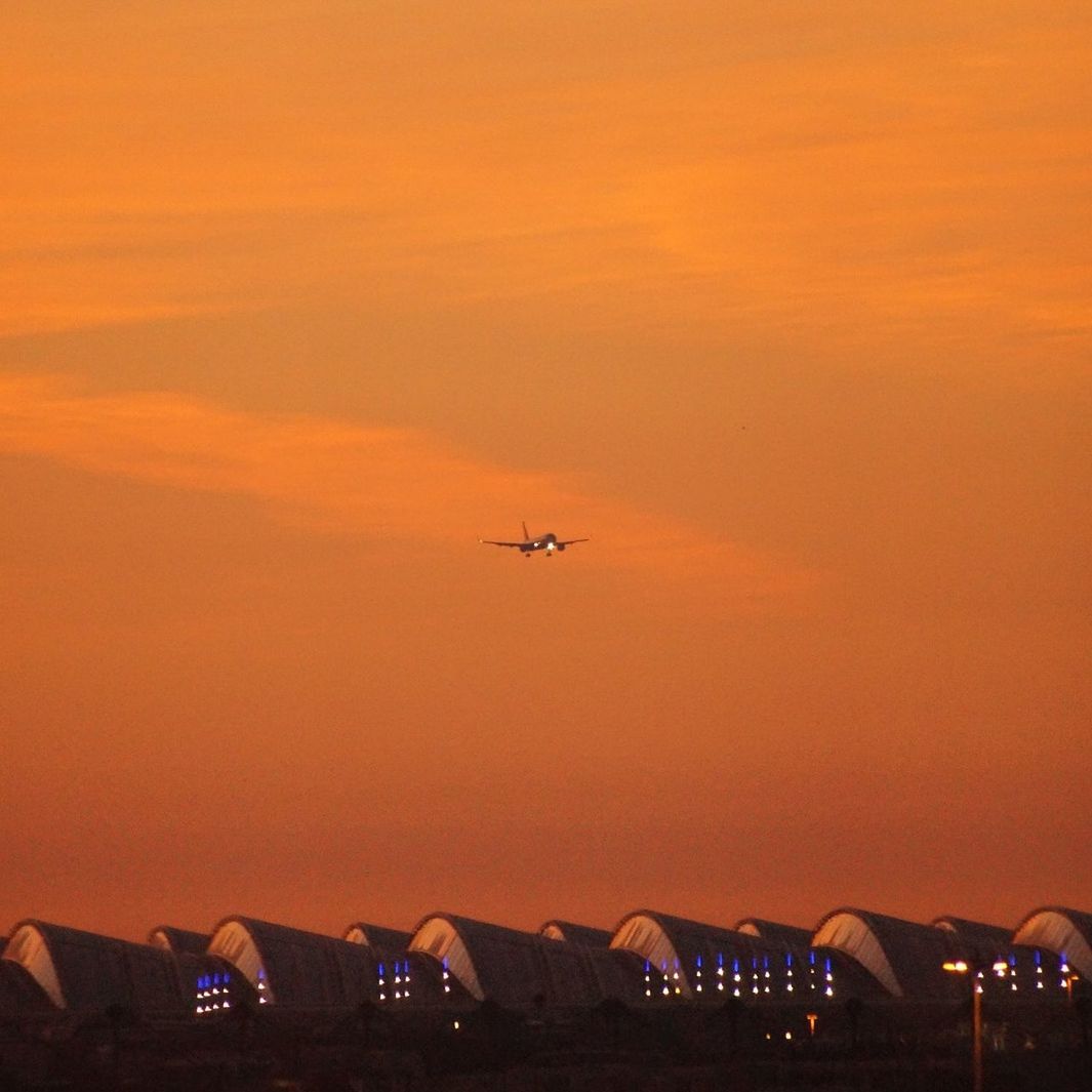 LOW ANGLE VIEW OF AIRPLANE FLYING IN SKY DURING SUNSET