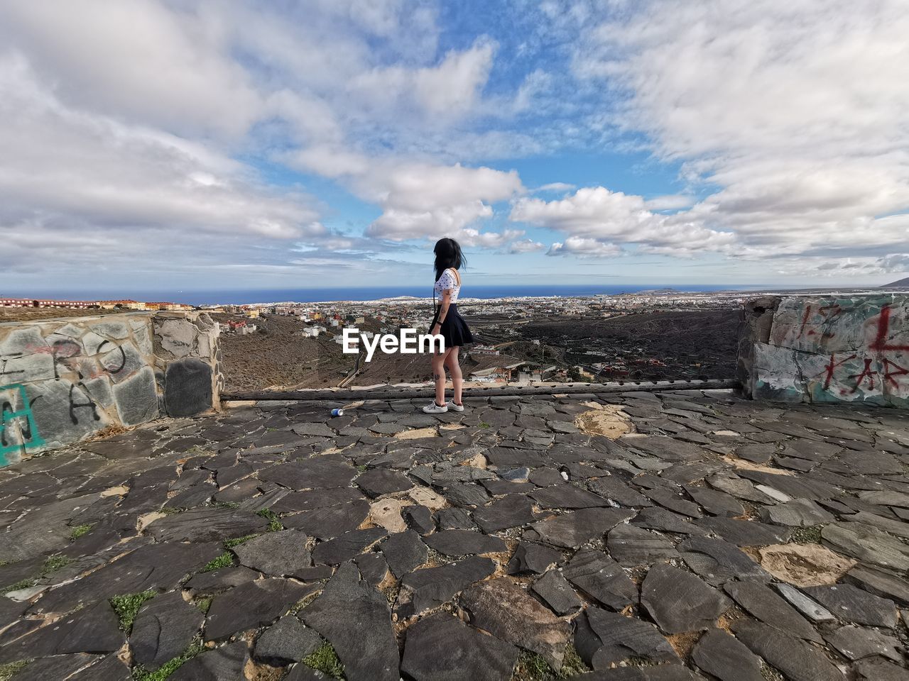 Side view of woman standing by sea against sky