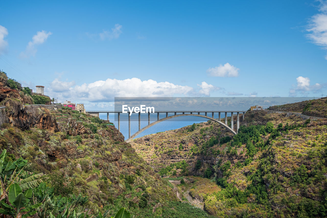 A bridge at the end of a gorge in front of the sea and blue sky
