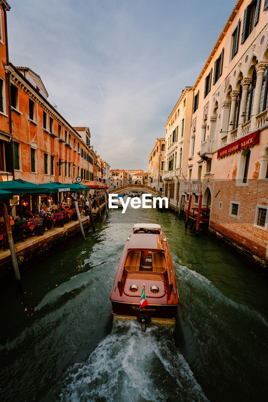 Typical venetian boat while sailing on characteristic tourist canal