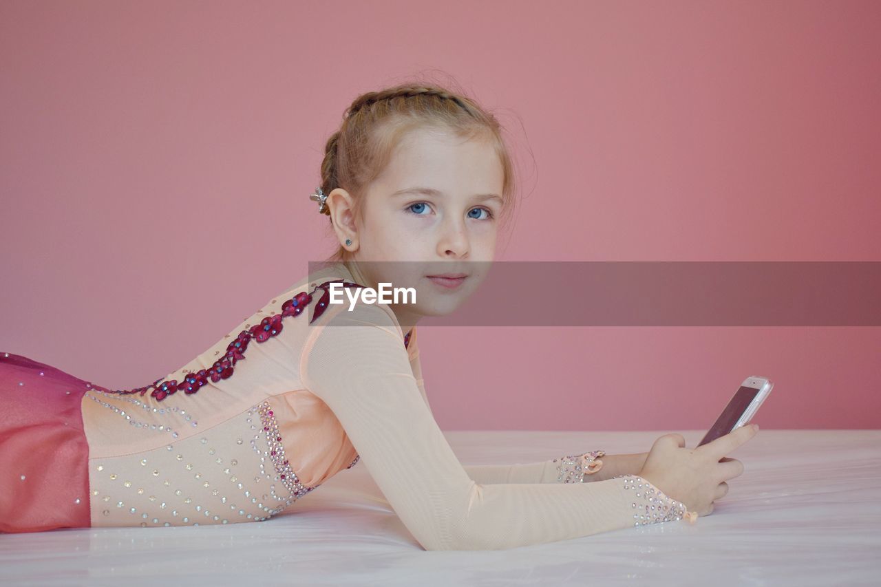 Portrait of cute girl using mobile phone on bed