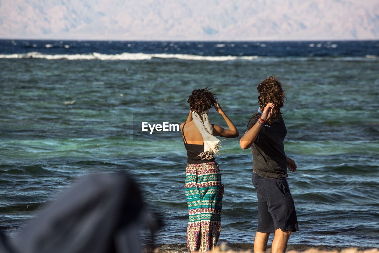 Rear view of people standing by sea