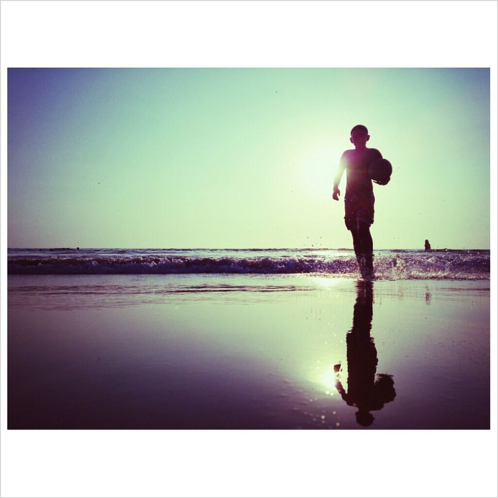 Boy with football at shore