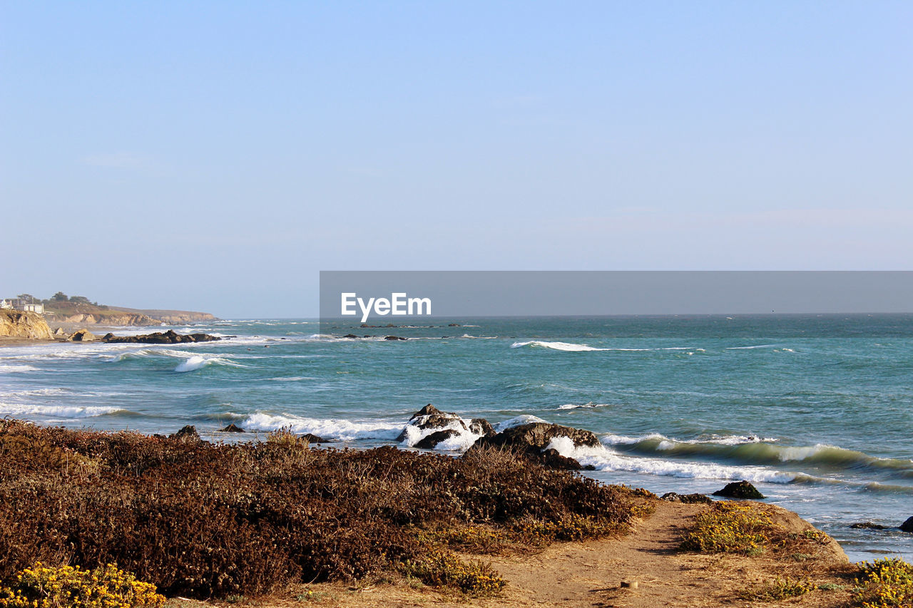 sea, water, land, beach, body of water, sky, shore, ocean, scenics - nature, beauty in nature, horizon, nature, coast, horizon over water, wave, tranquility, rock, cliff, tranquil scene, travel destinations, day, clear sky, sand, vacation, no people, coastline, motion, travel, cove, bay, outdoors, terrain, tourism, environment, wind wave, idyllic, holiday, sunny, copy space, blue, non-urban scene, trip, sports, landscape, sunlight, seascape, water sports