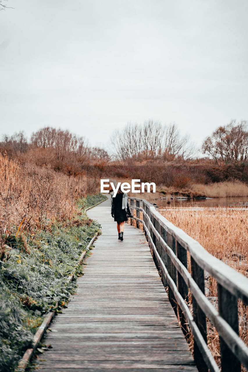 Rear view of woman walking on footbridge